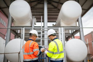İki bakım mühendisi büyük bir benzin deposunun durumunu inceliyor.