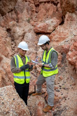 Jeologlar bir taş ocağında kazılan taşları toplar ve türlerini belirlemek için incelerler.