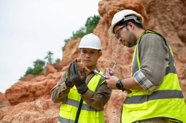 Jeologlar mineralleri bulmak için dağ toprağının durumunu analiz ediyorlar.