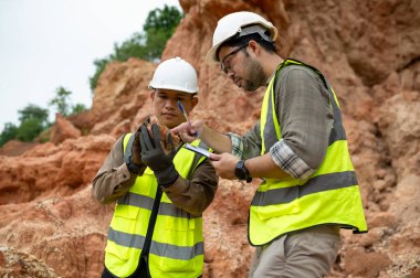 Jeologlar mineralleri bulmak için dağ toprağının durumunu analiz ediyorlar.