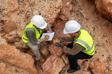 Jeologlar mineralleri bulmak için dağ toprağının durumunu analiz ediyorlar.