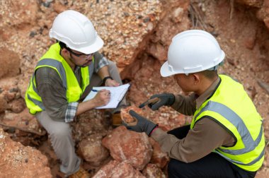 Jeologlar mineralleri bulmak için dağ toprağının durumunu analiz ediyorlar.