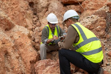 Jeologlar mineralleri bulmak için dağ toprağının durumunu analiz ediyorlar.