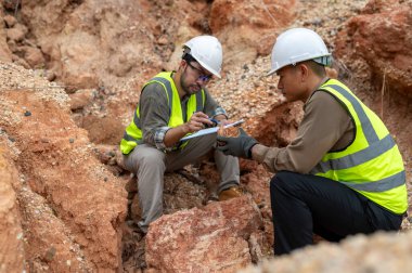 İki jeolog maden analizi için bir dağda toprak örnekleri topluyor.