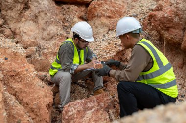 İki jeolog maden analizi için bir dağda toprak örnekleri topluyor.