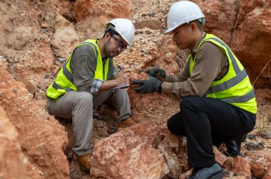 İki jeolog maden analizi için bir dağda toprak örnekleri topluyor.