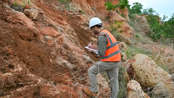 Jeolog, dağ alanındaki toprak ve kaya katmanlarının özelliklerini kaydediyor.