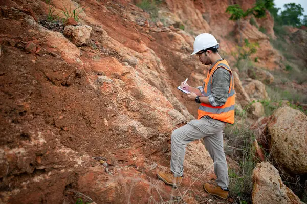 Jeolog, dağ alanındaki toprak ve kaya katmanlarının özelliklerini kaydediyor.