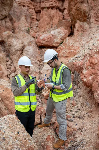 Jeologlar bir taş ocağında kazılan taşları toplar ve türlerini belirlemek için incelerler.