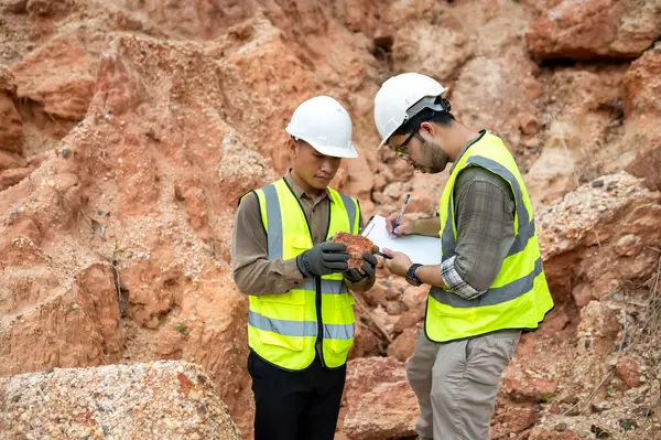 Jeologlar mineralleri bulmak için dağ toprağının durumunu analiz ediyorlar.
