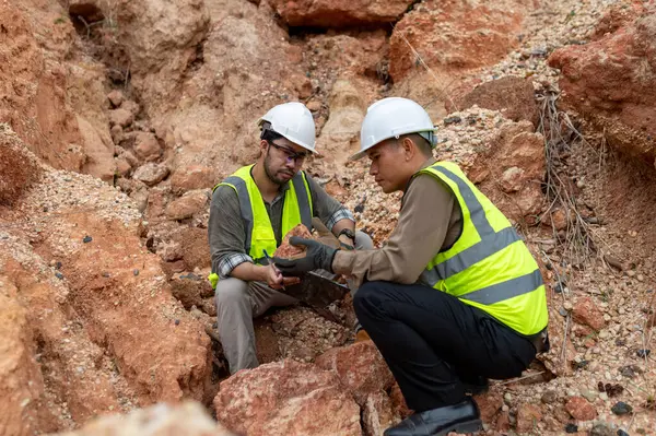 İki jeolog maden analizi için bir dağda toprak örnekleri topluyor.