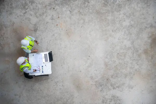 İki mimarın üst görüntüsü binanın yapısal planlarını hazırlıyor ve inşaatı planlıyor.