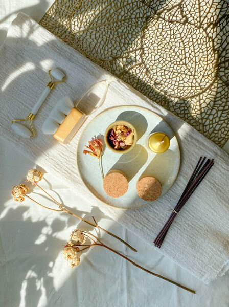 Spa composition with natural elements and textures. Spa setting for a serene beauty routine. Facial massage jade roller, natural brush, containers for storing cosmetics, incense sticks