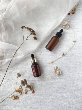 Şeffaf kumaş arka planında serum şişeleri. Yüz bakımı için kozmetik ürünleriyle harika bir kompozisyon