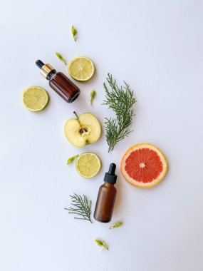 Serum şişeleri ve hafif arka planda meyveler olan bir kompozisyon. Yenilenme için C vitamini içeren kozmetikler. Yukarıdan görüntüle
