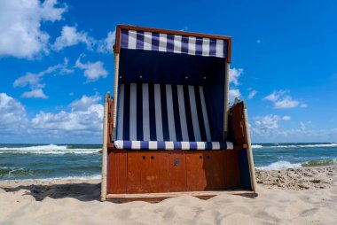Polonya, Jastarnia 'da açık mavi gökyüzünün altında Baltık Denizi dalgalarıyla kumlu sahilde plaj sandalyesi.