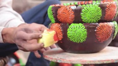 Yetenekli bir işçi ya da işçi canlı renkler ve süngerle kilden bir tencereyi boyar, geleneksel zanaat ve sanatsal teknikleri el yapımı bir çömlek dekorasyonu sürecinde sergiler. 4k Video 50 fps