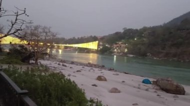 Rishikesh 'teki Ganga Nehri' ndeki kumsalda yaz aylarında sabahın erken saatlerinde Ram Jhula ile kum ve taşlar vardı.