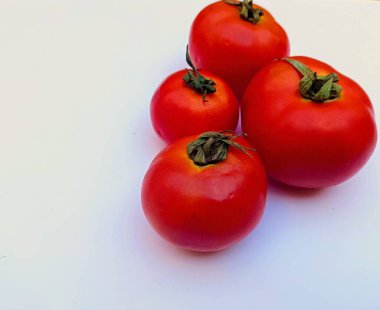 Beyaz arka planda kırmızı domates. Bu, dünya çapında farklı yemek ve salatalarda kullanılabilen lezzetli ve sağlıklı bir yiyecek olarak kabul edilir.