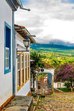 Tarihi Tiradentes şehrinde arka planda dağlar ve ormanlar olan eski renkli koloni evleri.