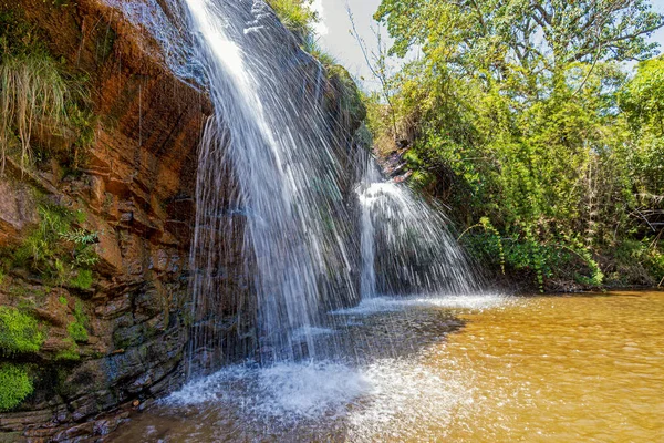 Waterfall among the rocks and forest in the Muaimii environmental reserve in the state of Minas Gerais on a sunny day