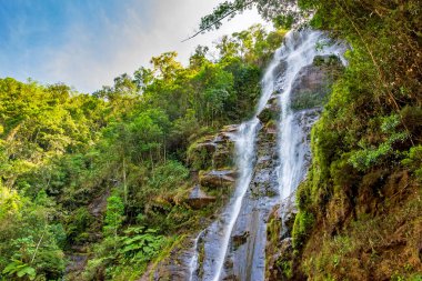 Brezilya 'nın Minas Gerais eyaletindeki yağmur ormanlarının yoğun bitki örtüsü ve kayaları arasında şelale