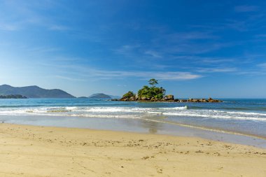Sao Paulo 'nun kuzey kıyısındaki Ilhabela' da gün batımında denizin önünde duran kadın.