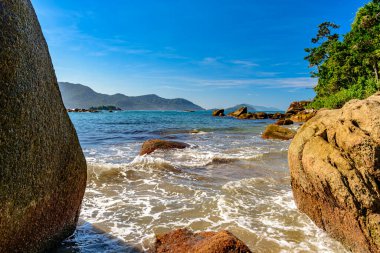 Sao Paulo 'nun kuzey kıyısındaki Ilhabela' da gün batımında denizin önünde duran kadın.