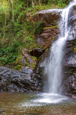 Brezilya 'nın Minas Gerais eyaletindeki yağmur ormanlarındaki kayalar ve bitki örtüsü arasında şelale
