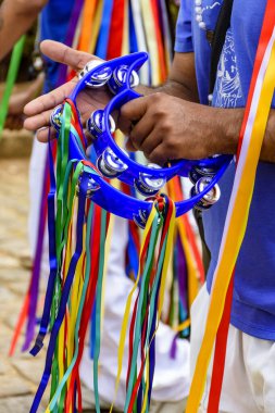 Geleneksel bir Brezilya dini festivalinde, tef çalan ve enstrümanı renkli kurdelelerle süslenmiş biri.