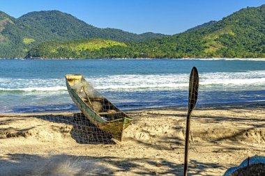 Canoe and fishing net on Castelhanos beach on Ilhabela island in Sao Paulo clipart