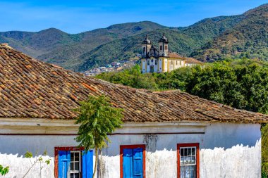 Tarihi Ouro Preto şehrinin arka planında barok kilisesi ve dağı olan eski bir sömürge evi.
