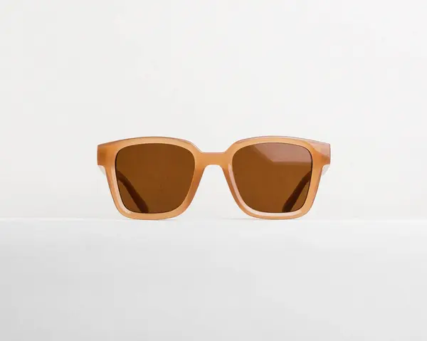 Beyaz arka planda gösterilen, kahverengi mercekli, modaya uygun kare güneş gözlüğü.
