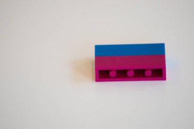 Tasarımda basitlik ve yaratıcılığı vurgulayan mavi ve pembe bölümlü renkli bir yapı taşının yakın çekimi. Çocukluk, hayal gücü ve minimalizm kavramları için ideal..