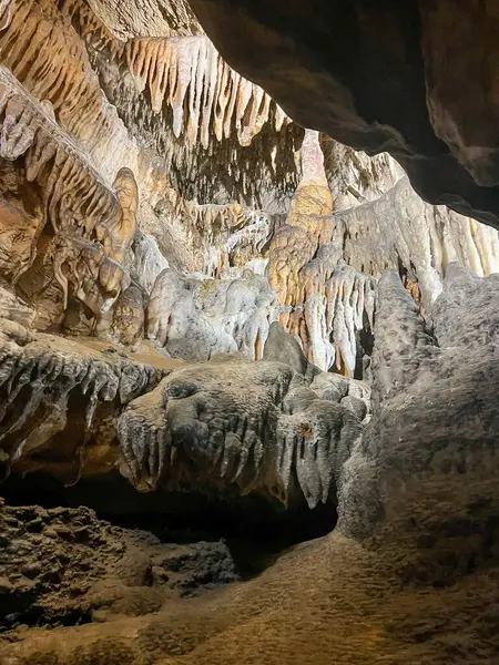 Sivri sarkıtları ve yuvarlak dikitleri vurgulayan doğal bir mağara iç mekanının büyüleyici bir keşfi dünyevi tonlar altında nefes kesici oluşumlar yaratıyor..