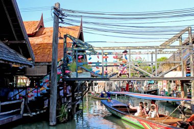 A floating market in Thailand showing colorful boats and traditional structures reflecting the local culture clipart