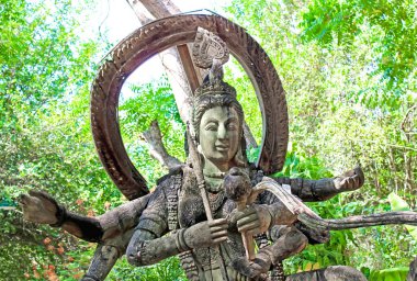 Karmaşık antik Budist tanrı heykeli doğal orman ortamında yer alıyor, huzur ve maneviyat yayıyor..