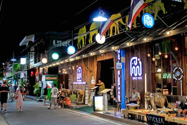 Canlı dükkanlar, neon ışıklar ve turistlerle dolu hareketli bir atmosfer ile aydınlatılmış gece sokak pazarı.