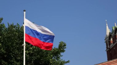 Güneşli bir günde Moskova 'daki Kremlin kulesinin yanında dalgalanan Rus bayrağı. Geleneksel mimari ve kültürel mirasın sergilendiği ulusal gurur ve tarihin bir sembolü.