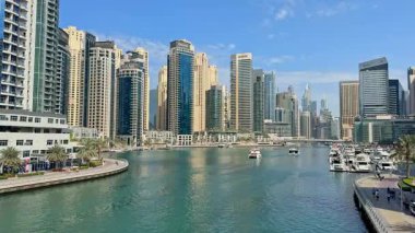Dubai Marina 'da modern gökdelenler, rıhtım koridorları, lüks yatlar. Canlı turistik yerler, çarpıcı manzaralar, yemekler, deniz kenarında boş zaman aktiviteleri sunuyor. 16 Şubat 2025, Dubai, BAE