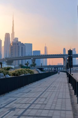  Dubai Tasarım Bölgesi 'ndeki güzel rıhtım güvertesi Dubai silueti ve Burj Halife üzerinde puslu bir günbatımı ile. Yüksek kalite fotoğraf