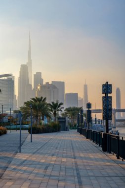  Dubai Tasarım Bölgesi 'ndeki güzel rıhtım güvertesi Dubai silueti ve Burj Halife üzerinde puslu bir günbatımı ile. Yüksek kalite fotoğraf