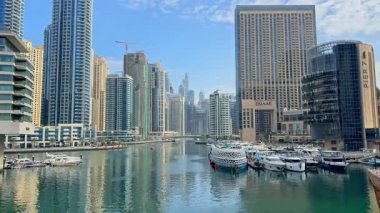 Dubai Marina 'da modern gökdelenler, rıhtım koridorları, lüks yatlar. Canlı turistik yerler, çarpıcı manzaralar, yemekler, deniz kenarında boş zaman aktiviteleri sunuyor. 16 Şubat 2025, Dubai, BAE