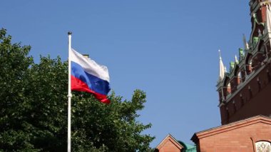 Güneşli bir günde Moskova 'daki Kremlin kulesinin yanında dalgalanan Rus bayrağı. Geleneksel mimari ve kültürel mirasın sergilendiği ulusal gurur ve tarihin bir sembolü.