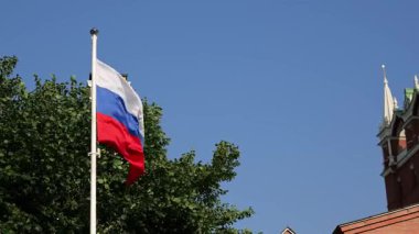 Güneşli bir günde Moskova 'daki Kremlin kulesinin yanında dalgalanan Rus bayrağı. Geleneksel mimari ve kültürel mirasın sergilendiği ulusal gurur ve tarihin bir sembolü.