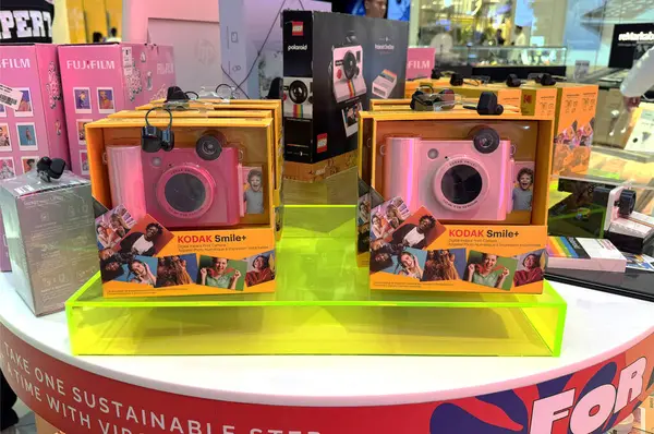Renkli bir elektronik mağazasında Kodak 'ın pembe renkli fotoğraf makinesi görüntüsü. Eğlenceli hediye fikri, canlı ambalaj ve modern perakende satış ortamında retro fotoğrafçılık.
