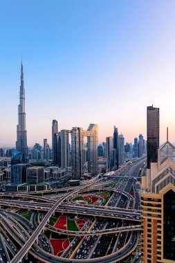 Günbatımında modern gökdelenler, aydınlanmış otoyollar, yoğun trafik ve yoğun kentsel gelişim ile Dubai 'nin havadan şehir manzarası. Dubai hızla büyüyen metropol fütüristik silueti ve hayat dolu