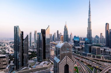 Günbatımında modern gökdelenler, aydınlanmış otoyollar, yoğun trafik ve yoğun kentsel gelişim ile Dubai 'nin havadan şehir manzarası. Dubai hızla büyüyen metropol fütüristik silueti ve hayat dolu