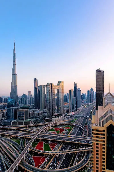 Günbatımında modern gökdelenler, aydınlanmış otoyollar, yoğun trafik ve yoğun kentsel gelişim ile Dubai 'nin havadan şehir manzarası. Dubai hızla büyüyen metropol fütüristik silueti ve hayat dolu