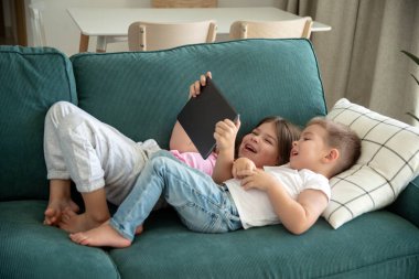 Çocuklar oturma odasındaki kanepede uzanıp tablete bakıyorlar. Ebeveyn araması yapmak, video oyunu oynamak, çevrimiçi içerik izlemek, internette gezinmek. Yüksek kalite fotoğraf